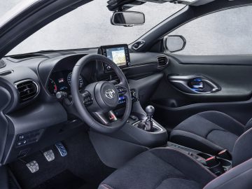 Binnenaanzicht van de Toyota GR Yaris met het stuur, het dashboard en de voorstoelen, met de nadruk op hightech bedieningselementen en sportieve designelementen.