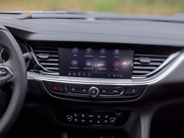 Binnenaanzicht van een Opel Insignia met een dashboard met touchscreen, een stuur aan de linkerkant en een onscherpe achtergrond buiten.
