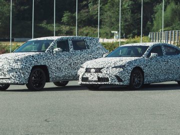 Twee gecamoufleerde Lexus-auto's die DIRECT4-tests ondergaan, staan naast elkaar geparkeerd op een zonnig buitenterrein.