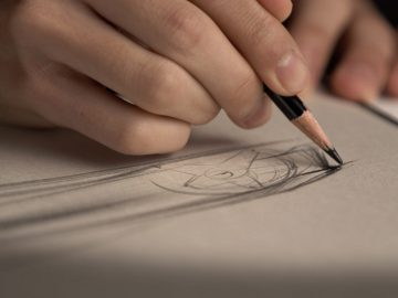 Een close-up van een hand die met een potlood een geometrisch ontwerp schetst op structuurpapier, geïnspireerd op de Lexus DIRECT4-technologie.
