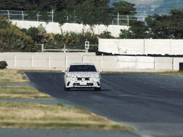 Een gecamoufleerde auto van Lexus die wordt getest op een racecircuit en zijn prestaties en rijeigenschappen laat zien in een gecontroleerde omgeving.