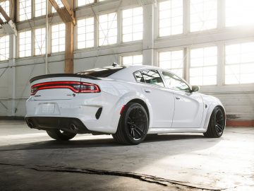 Witte RAM 1500 geparkeerd in een zonovergoten magazijn, waarbij de achterkant en het profiel goed uitkomen tegen industriële ramen.