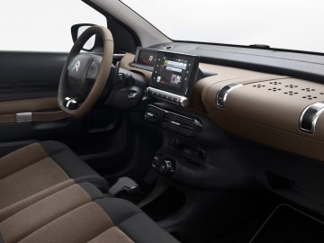 Binnenaanzicht van een moderne Citroën C4 Cactus met het stuur, het dashboard en het infotainmentsysteem in een tweekleurig bruin en zwart kleurenschema.