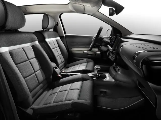 Binnenaanzicht van een Citroën C4 Cactus met de voor- en achterstoelen, het dashboard en het stuur in een donker kleurenschema.