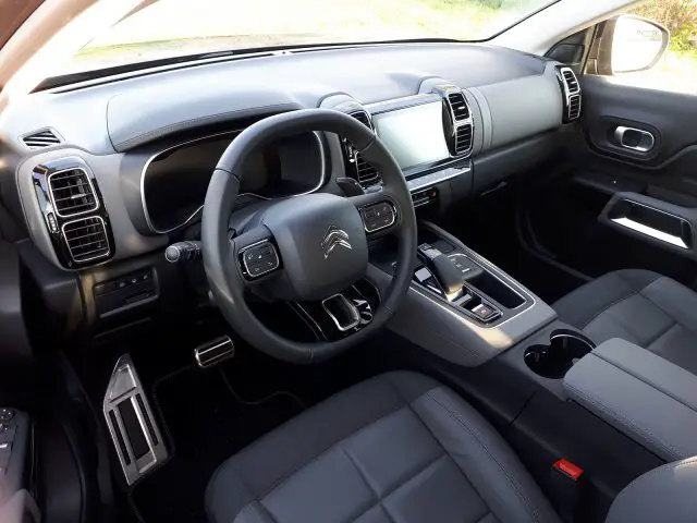 Binnenaanzicht van een Citroën C5 Aircross Hybrid met het stuur, het dashboard, de middenconsole en de zwartleren stoelen.