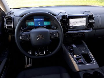 Binnenaanzicht van een Citroën C5 Aircross Hybrid met het stuur, het digitale dashboard en het centrale touchscreen-navigatiesysteem.