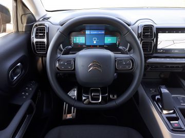 Binnenaanzicht van de C5 Aircross Hybrid met het stuur met een Citroën-logo en een digitaal dashboarddisplay.