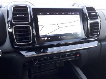 Autodashboard in de C5 Aircross Hybrid met een centraal touchscreen met een navigatiekaart, omgeven door ventilatieopeningen en verschillende bedieningselementen.