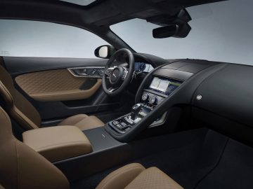 Binnenaanzicht van een moderne Jaguar F-TYPE met de nadruk op de bestuurderszijde, met een stuur, dashboard en lederen stoelen.