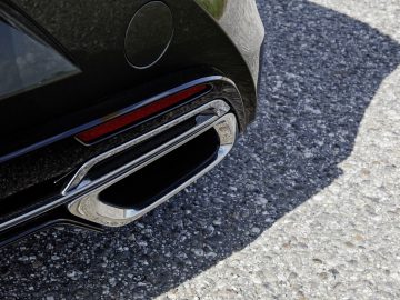 Close-up van het achterste uitlaatsysteem van een Lexus LC 500 Convertible met chromen details op een asfaltachtergrond.