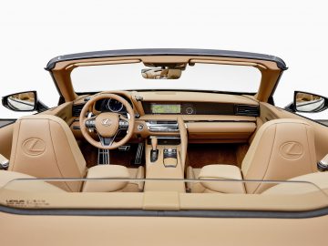 Binnenaanzicht van een luxe Lexus LC 500 Convertible, met bruinleren stoelen, een houten dashboard en het stuur met een logo.