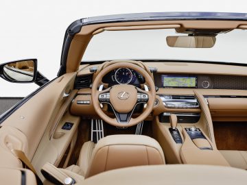 Binnenaanzicht van een Lexus LC 500 Convertible met een bruin lederen cabine, stuurwiel, dashboard met digitale displays en een open dak.