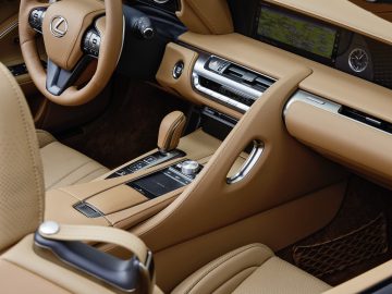Binnenaanzicht van een Lexus LC 500 Convertible met bruinleren stoelen, een gedetailleerd dashboard en moderne bedieningselementen.