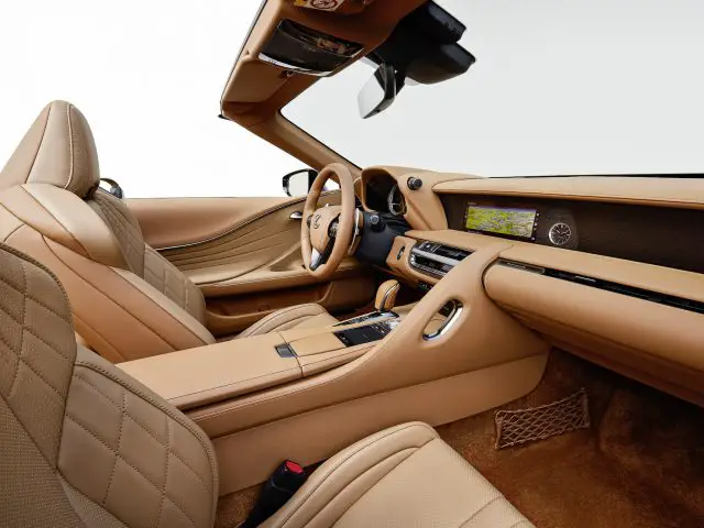 Binnenaanzicht van de Lexus LC 500 Convertible met bruin lederen stoelen, een verfijnd dashboard met digitale displays en houten accenten.