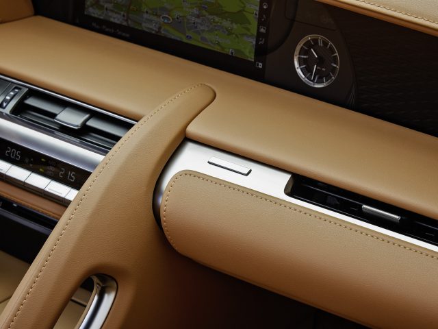 Close-up van het luxueuze interieur van een Lexus LC 500 Convertible met een bruin lederen dashboard, klimaatbeheersingssysteem en een geïntegreerd navigatiescherm.
