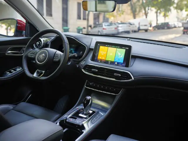 Binnenaanzicht van de MG EHS Plug-in Hybrid met een stuur met logo, digitaal dashboarddisplay en lederen stoelen.