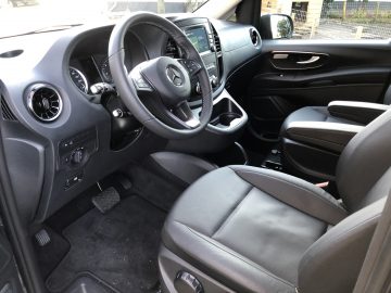 Binnenaanzicht van een Mercedes-Benz Vito met de bestuurdersstoel, het stuur, het dashboard en de bedieningselementen in een strak en modern ontwerp.