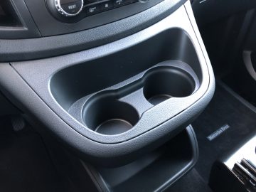 Interieur van een Mercedes-Benz Vito met een dubbele bekerhouder op de middenconsole, met textuurdetails en zichtbaar automerklabel.