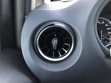 Close-up van een Mercedes-Benz Vito-ventilatierooster op het dashboard met een gestructureerd, donkergrijs oppervlak.