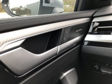 Binnenaanzicht van een Volkswagen Arteon Shooting Brake-deur met raam- en spiegelbedieningsknoppen, met een luidspreker met het merk "Bang & Olufsen.