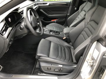 Binnenaanzicht van een moderne Volkswagen Arteon Shooting Brake met lederen stoelen, stuur aan de linkerkant, middenconsole en dashboard zichtbaar.