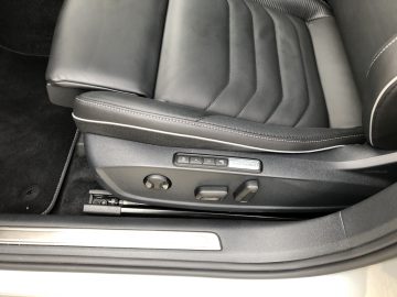 Close-up van de zwartleren stoel van een Volkswagen Arteon Shooting Brake met elektronische verstelknoppen op het zijpaneel.