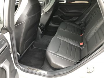 Binnenaanzicht van een Volkswagen Arteon Shooting Brake met zwartleren achterbank en deurpaneel, met vloerbedekking.