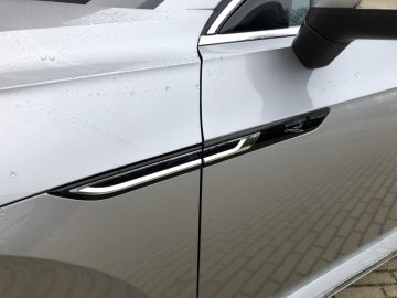Close-up van een Volkswagen Arteon Shooting Brake-autodeurkruk met regendruppels op het oppervlak.