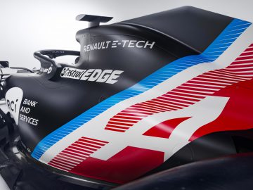 Close-up van een zwart-rode Formule 1-auto met sponsorlogo's en prominente Alpine-branding.