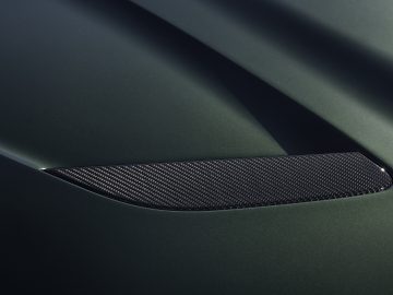 Close-up van de motorkap van een groene BMW M5 CS, met een strakke, zwarte ventilatieopening die in het ontwerp is geïntegreerd.