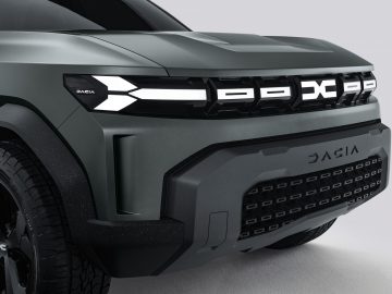 Close-up van het frontontwerp van de grijze Dacia Bigster Concept SUV, waarbij de details van de koplamp en de grille benadrukt worden.