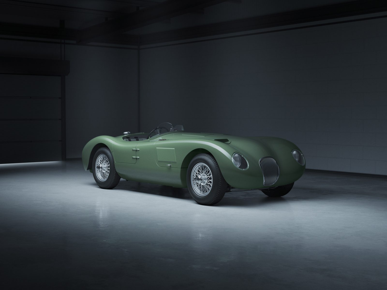 Een klassieke groene raceauto van het Jaguar C-type staat geparkeerd in een slecht verlichte garage, met strakke rondingen en vintage design met spaakwielen.
