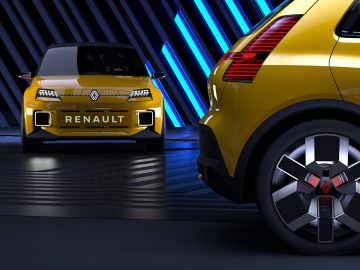 Twee Renault 5-auto's tentoongesteld in een futuristische setting met blauw verlichte strepen op de achtergrond.