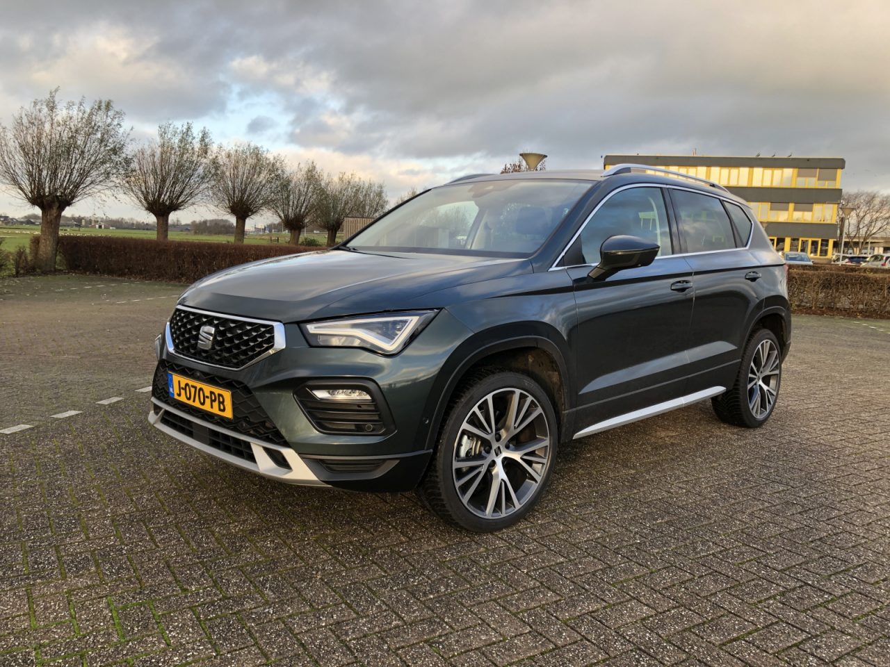 Een moderne donkergrijze Seat Ateca SUV die op een zonnige dag buiten geparkeerd staat, met opvallende koplampen en chromen accenten.