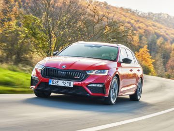 Een rode Skoda Octavia RS iV die over een bochtige weg rijdt, omringd door herfstbladeren.