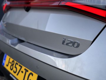 Close-up van de achterkant van een slanke zilveren Hyundai i20, met een deel van de gele kentekenplaat.