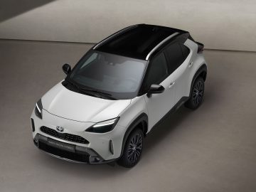 Een witte Toyota Yaris Cross Adventure Hybrid die binnen geparkeerd staat, vanuit een hoge hoek bekeken, met zijn strakke ontwerp en zwarte dak.