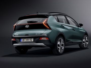 Een slanke, groene compacte SUV Hyundai Bayon wordt vanuit driekwart achteraanzicht getoond, met trots de achterlichten en kentekenplaat "OF HY 92".