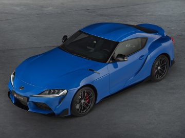 Op een betonnen ondergrond staat een blauwe Toyota GR Supra met een strak design geparkeerd.