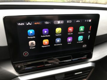 Op een scherm in de Cupra Leon e-Hybrid worden diverse apps weergegeven, waaronder navigatie, radio/media, telefoon, voertuiginstellingen, rijgegevens, volledige koppeling, gebruikers, instellingen en klimaatregeling.