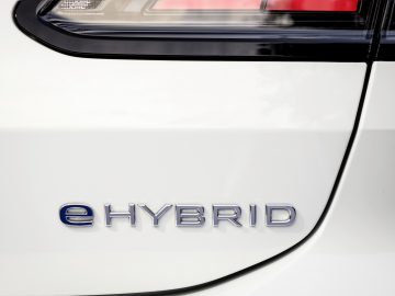Close-up van een Volkswagen Tiguan met een witte buitenkant met het "eHYBRID"-embleem bij het achterlichtcluster.
