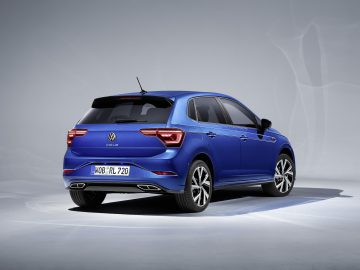 Een blauwe Volkswagen Polo hatchback wordt vanuit driekwart achteraanzicht getoond tegen een effen achtergrond, wat het strakke ontwerp benadrukt.