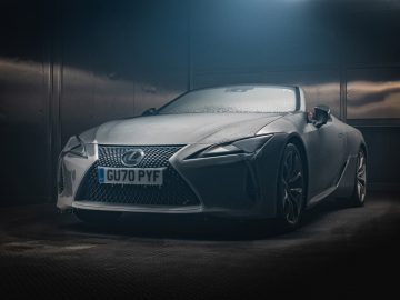 Een zilveren Lexus LC-cabriolet staat geparkeerd in een slecht verlichte garage, met de voorkant en de bestuurderszijde zichtbaar, met kenteken "GU70 PYF.