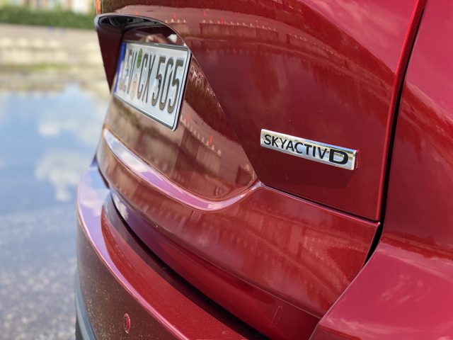 Close-up van de achterkant van een rode Mazda CX-5 met een "SKYACTIV D" -badge en een Europees kenteken beginnend met "BX 505".