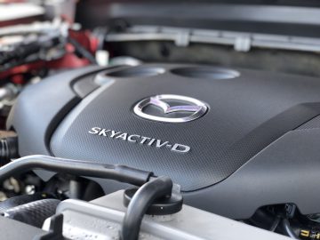 Close-up van een Mazda CX-5 SKYACTIV-D-motor met het Mazda-logo en de tekst "SKYACTIV-D" zichtbaar op de motorkap.