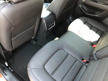 Achterbankaanzicht van een Mazda CX-5-interieur met bruinleren bekleding, een middenconsole en zwarte vloermatten.