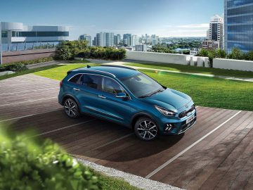 Een blauwe SUV, die het succes van de autoverkoop in april 2021 weerspiegelt, staat geparkeerd op een parkeerterrein op het dak met de skyline van de stad en moderne gebouwen op de achtergrond.