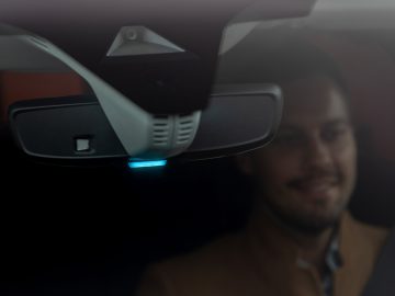Achteruitkijkspiegel met ingebouwde technologie in een Opel Grandland, met een lachende bestuurder zichtbaar op de achtergrond.
