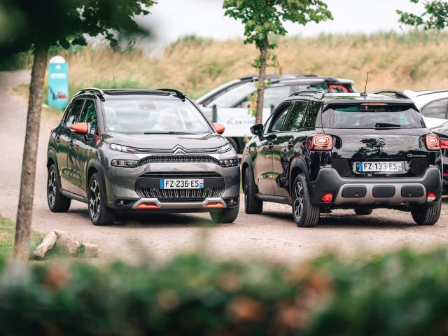 Twee geparkeerde Citroën C3 Aircross-auto's op een buitenterrein met bomen en andere voertuigen op de achtergrond.