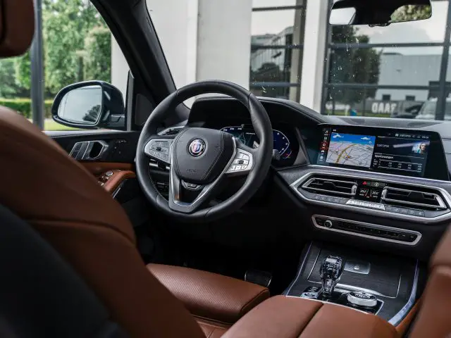 Het interieur van een BMW Alpina straalt luxe uit met zijn leren stuur, digitaal dashboard en groot touchscreen display met navigatie. De bruinleren stoelen maken de weelderige sfeer compleet.